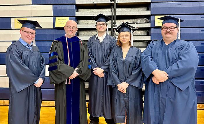 Spring 2023 graduates Joseph Gagermeier, 艾丽西亚Qatipi, 马修•沃尔夫, 诺亚·普兰克 standing with Teaching Professor 道格页面.